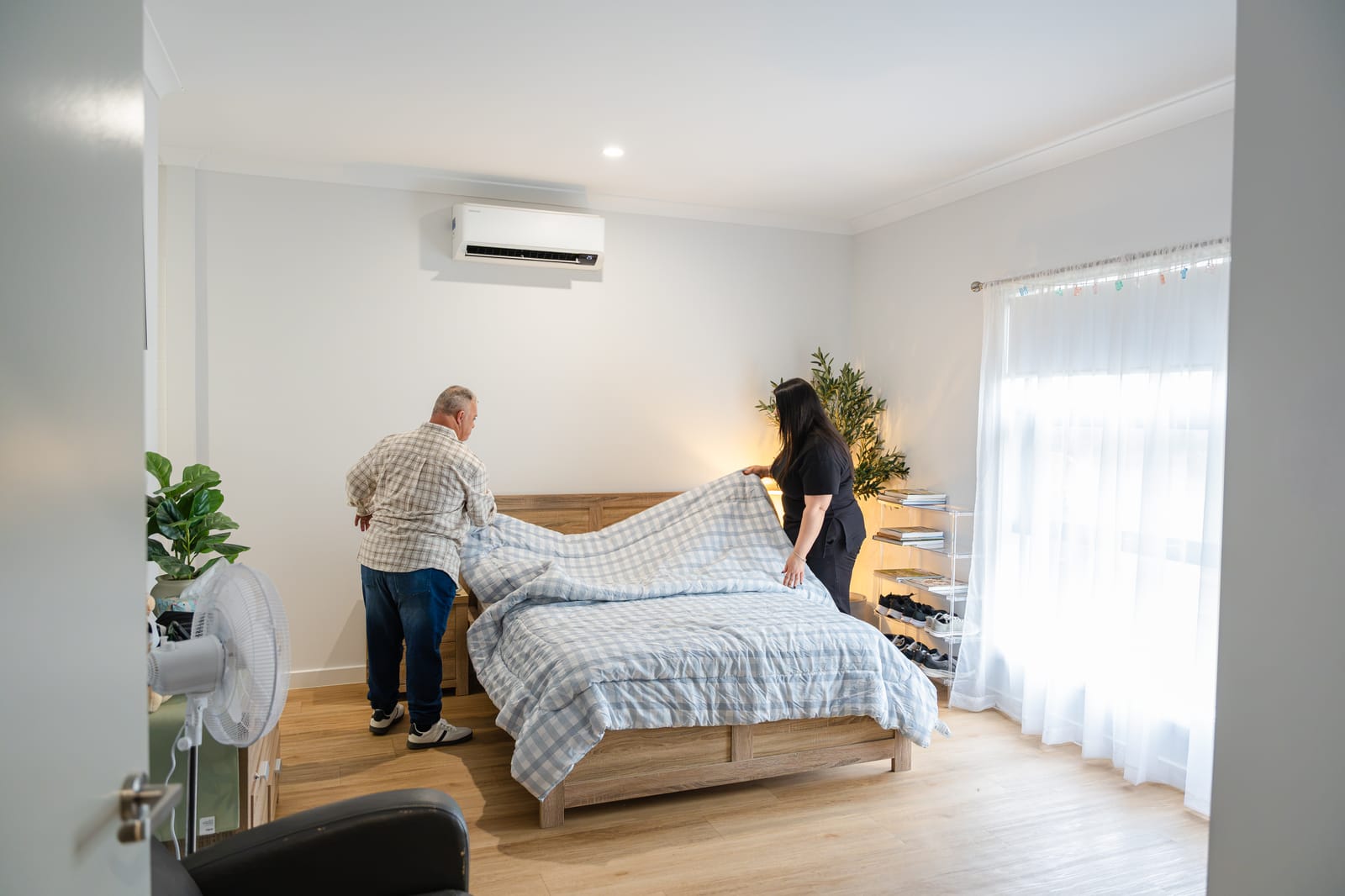 A QB Care participant and support worker making the bed together in his room
