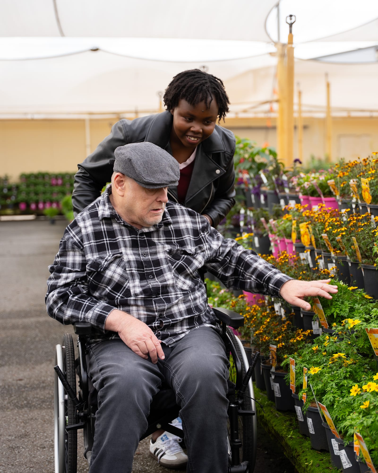 A QB Care resident choosing plants at a garden nursery with his support worker